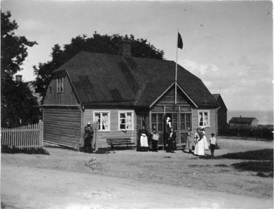 Trähus med flaggstång och familj